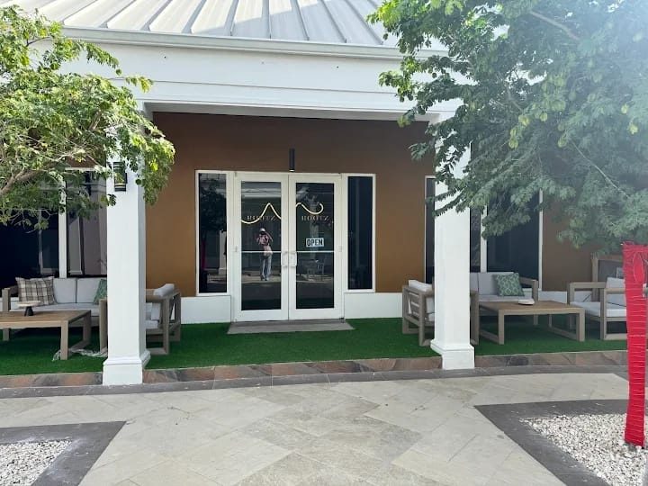 The ROOTZ entrance: white columns, glass doors and a patio with outdoor seating
