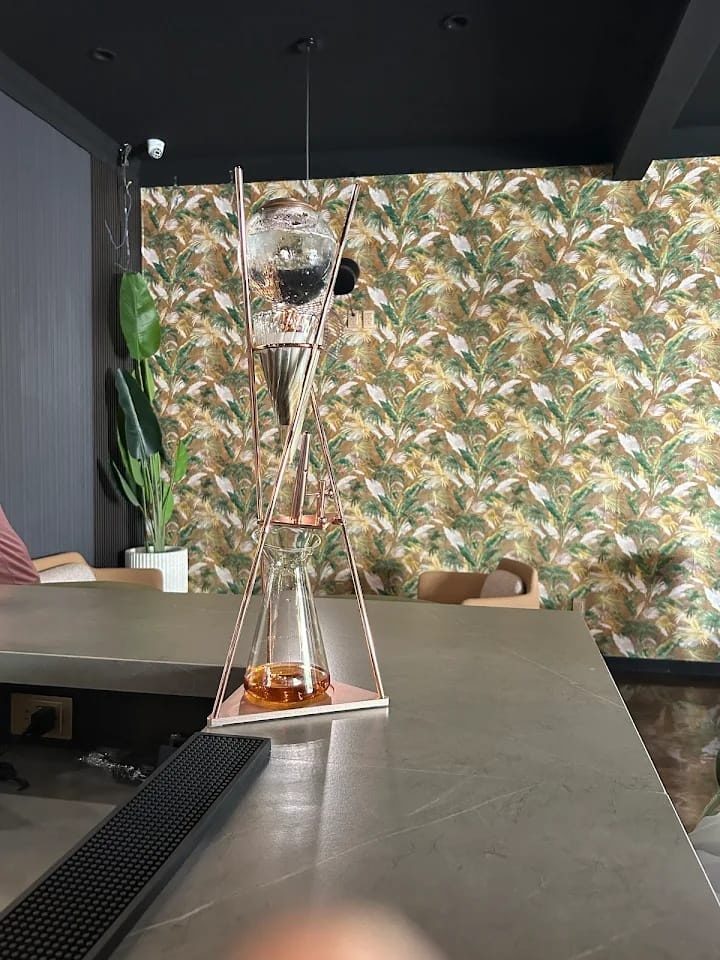 A glass tea tower on the ROOTZ bar, tropical wallpaper behind
